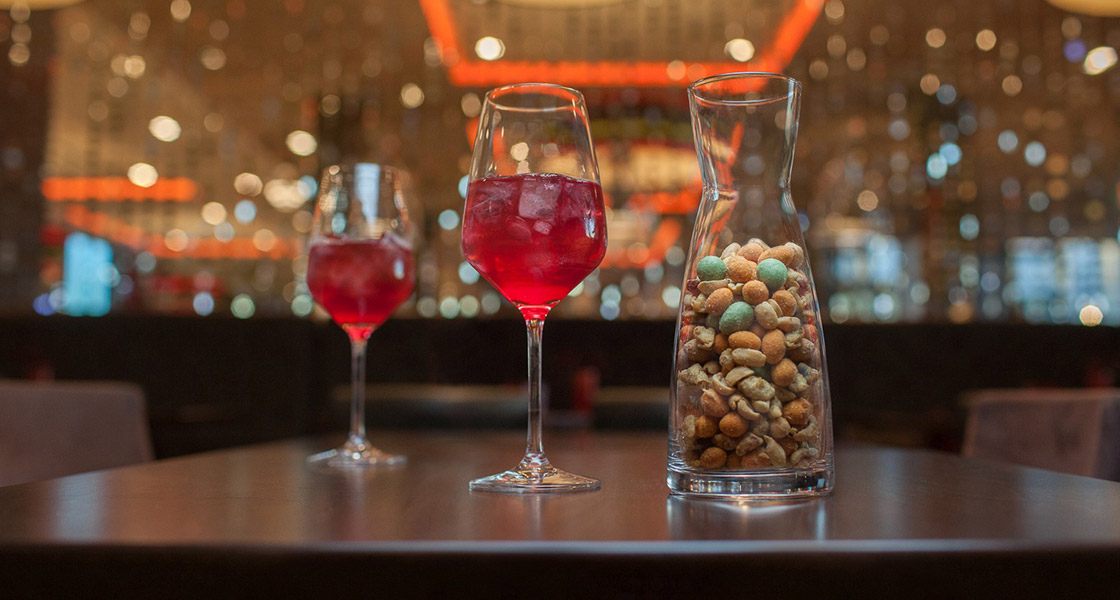 Zwei rote Drinks und eine CrackersCompany-Snackkaraffe in einer Hotelbar